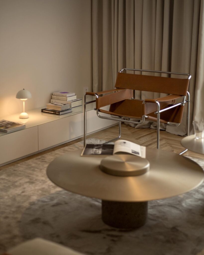 Cozy And Minimalist Interior Design Space With Leather Armchair, Books, And Lamp On Side Table