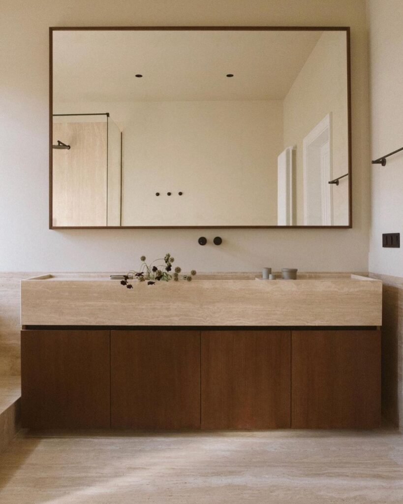 A Minimalist Bathroom Design With A Large Mirror And Wooden Vanity