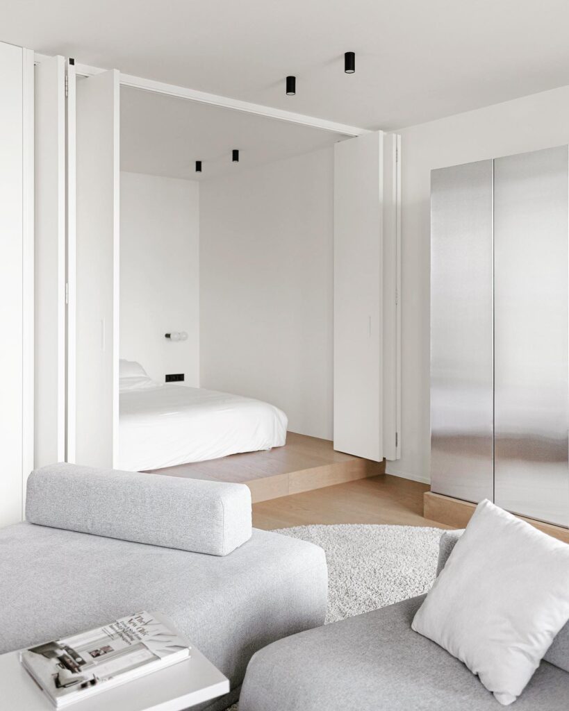 Minimalist Bedroom Design with White Walls, Gray Sofa, and Subtle Lighting