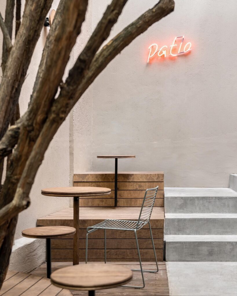 A Minimalist Cafe Interior With Wooden Furniture And Neon Signage