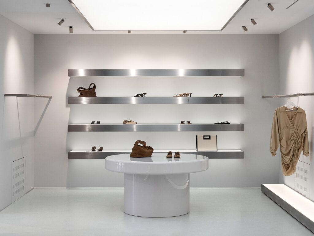 A minimalist retail display with floating shelves and a circular display pedestal