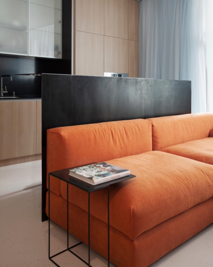 Modern Minimalist Interior Design With Orange Sofa, Black Accents, and Sleek Kitchen Area