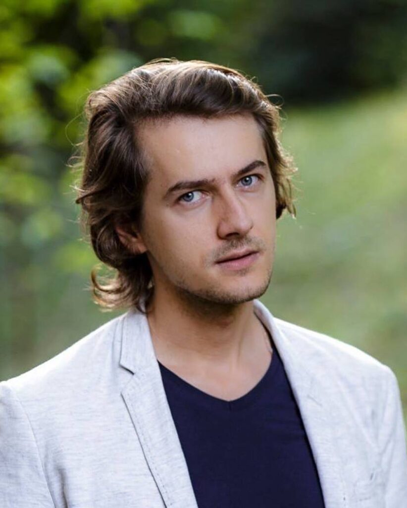 Thoughtful Portrait of Man with Curly Brown Hair and Blue Eyes