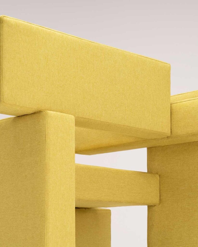 Close-up view of a yellow upholstered sofa or chair, showcasing the clean lines and geometric shapes of the Sivak+Partners design studio's interior design aesthetic.