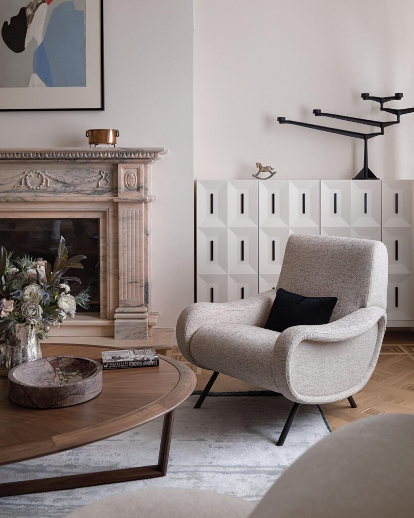 A cozy interior design scene featuring a fireplace, armchair, and decorative elements designed by Sivak+Partners.