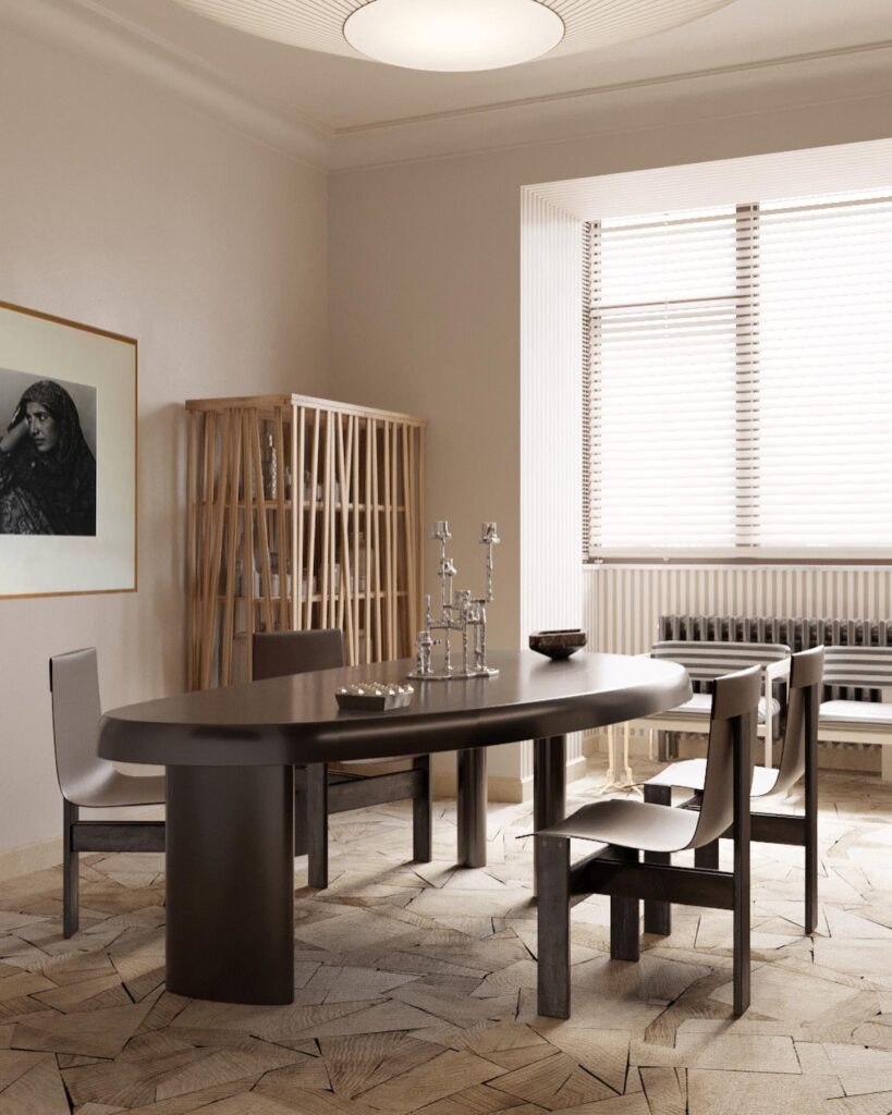 A minimalist dining room with a curved wooden table and chairs, framed wall art, and a wooden shelving unit.