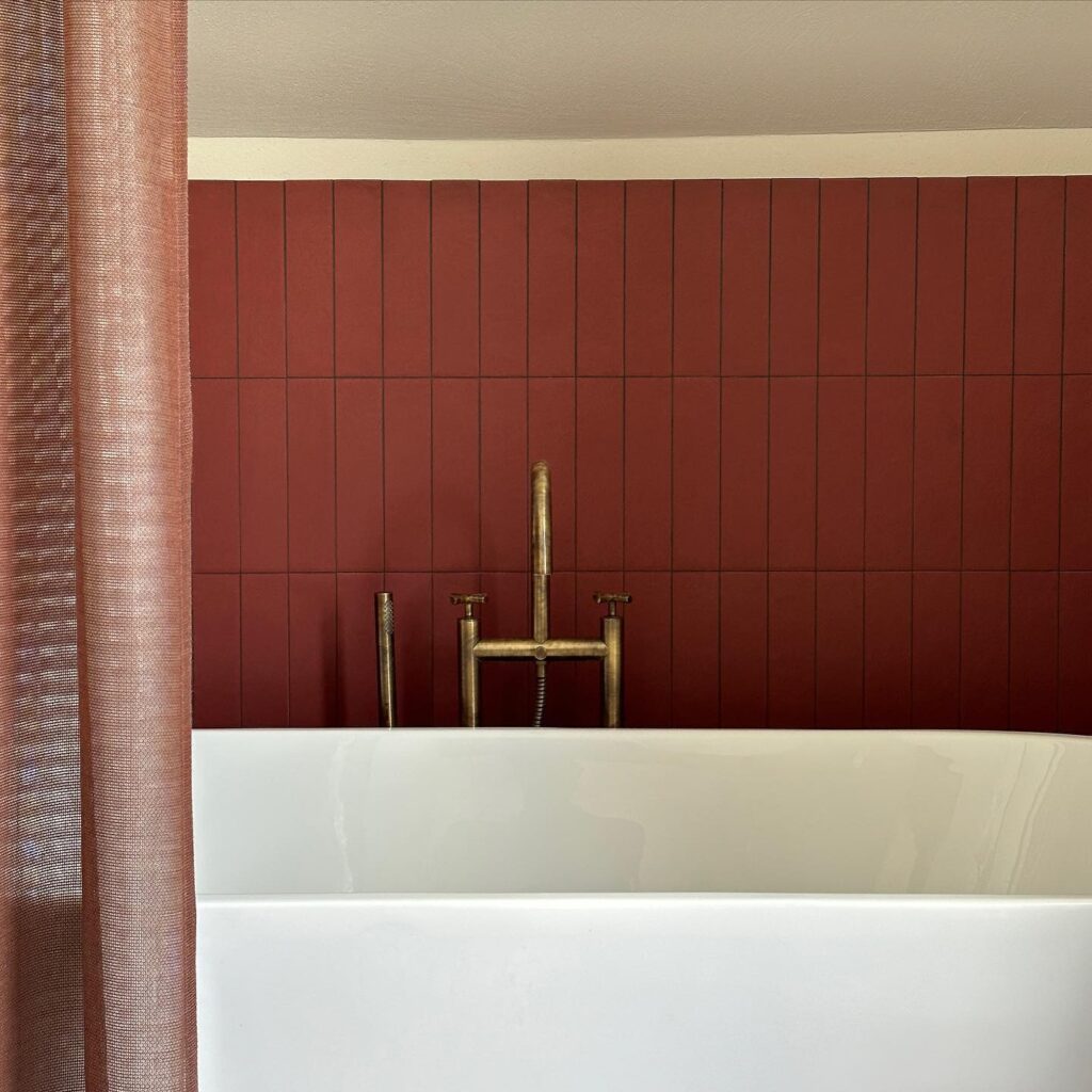 A Minimalist Bathroom Design with Red Tile Walls and a Vintage Faucet