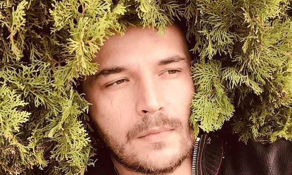 Partially Obscured Man's Face Amid Lush Green Foliage