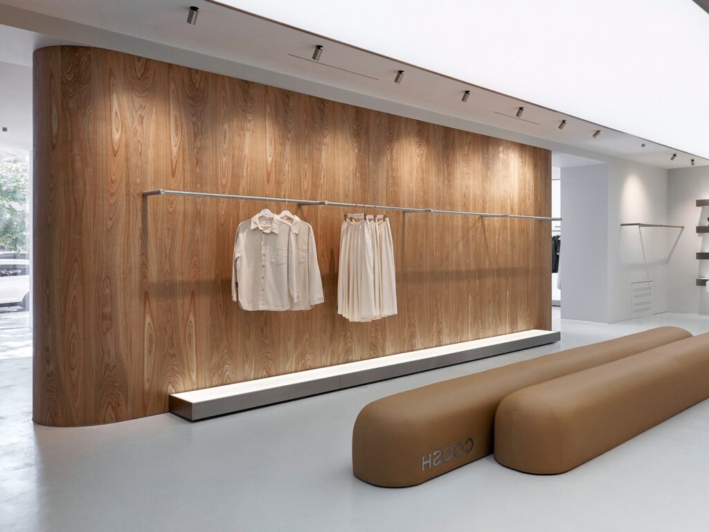 A Wooden Wall With Hanging Clothes Racks And Seating In A Modern Interior Design Setting.